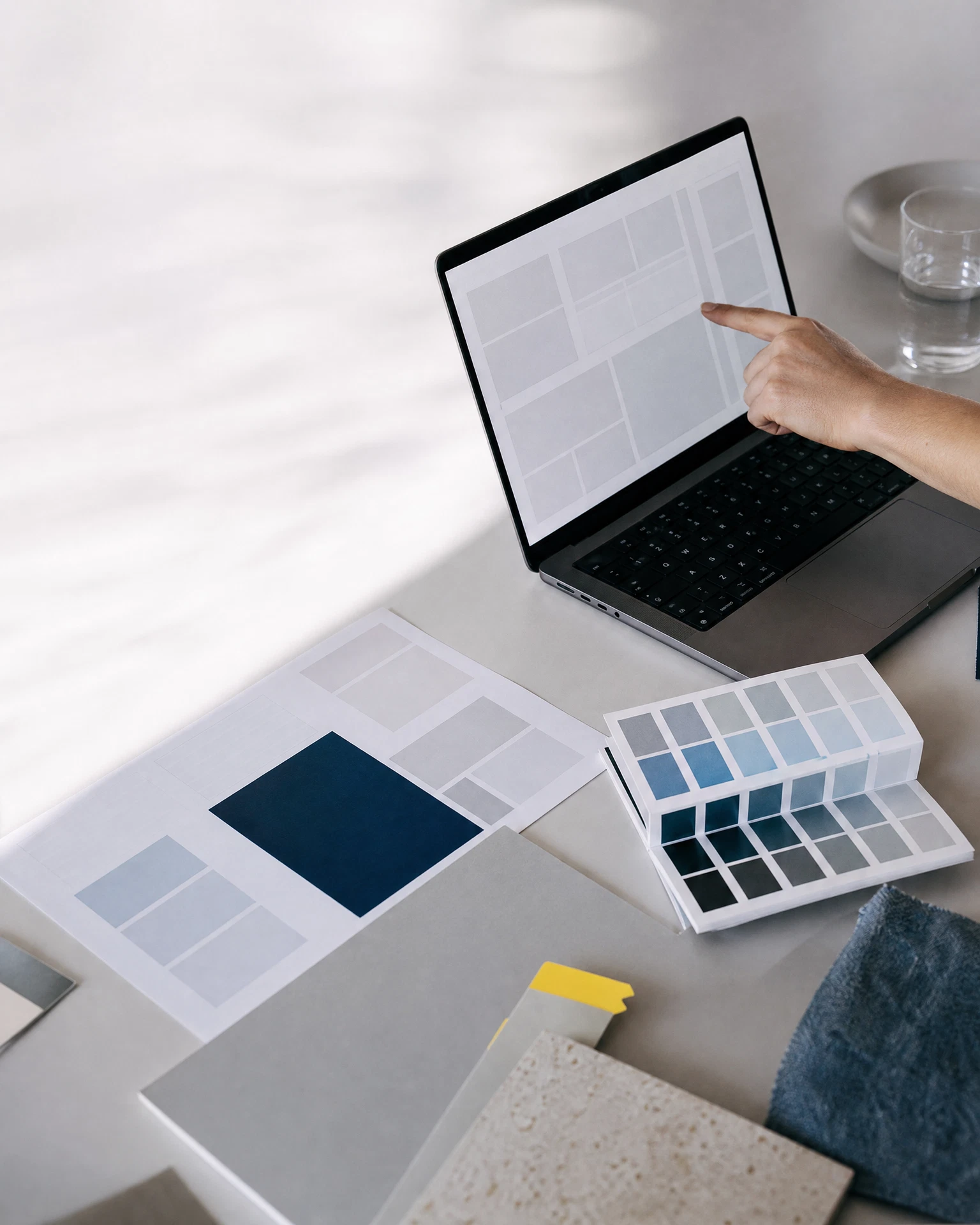 Arbeitsfläche mit Wireframe, Farbfächern und Laptop in einer kreativen Strategierunde.